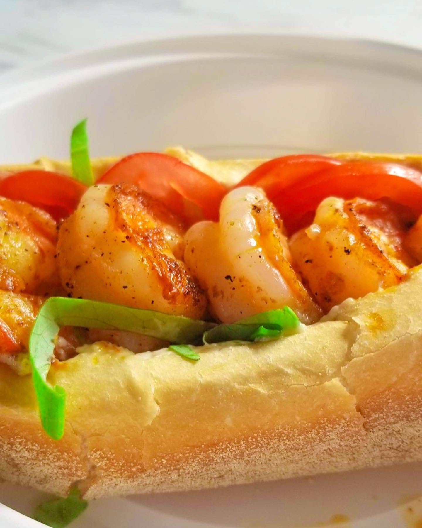 V9 Fried Shrimp Po'Boy with tomato and lettuce on a toasted roll