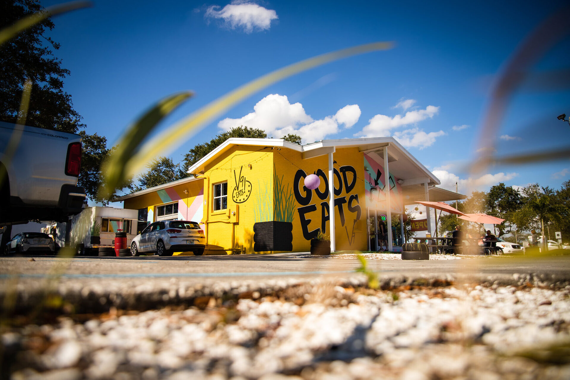 The sunflower-yellow V9 EATS building with its GOOD EATS mural under a blue sky