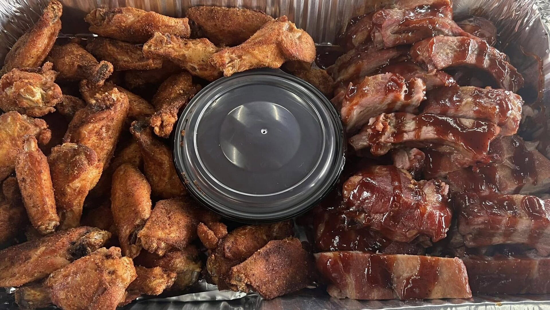 A party tray of V9 wings with dipping sauce